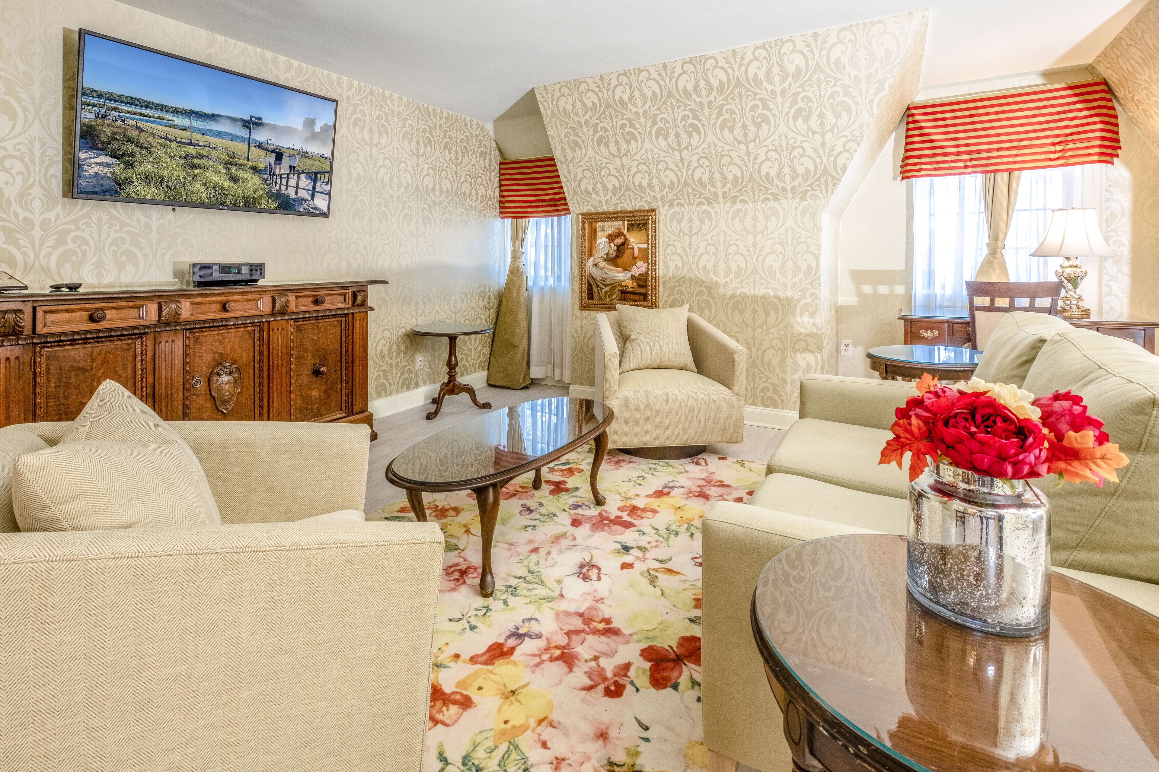 A living room with a sofa, armchairs, a coffee table, and a TV mounted on the wall.
