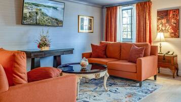 A living room with a sofa, a coffee table, and a TV mounted on the wall.