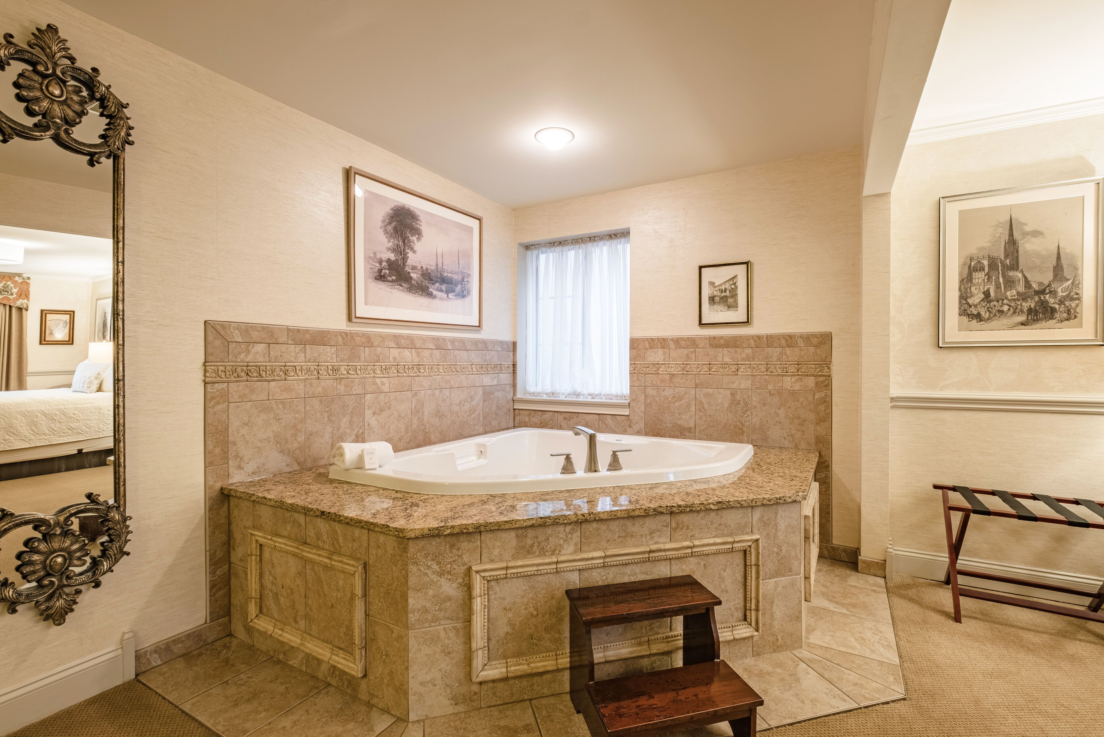 Ein Badezimmer mit freistehender Badewanne, Waschtisch, Spiegel und gerahmten Bildern an den Wänden.