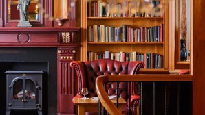 Una biblioteca con estanterías, chimenea y un sillón de cuero.
