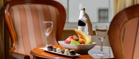 A dining table with a fruit bowl, a bottle of champagne, and two glasses.