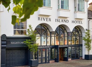 Fachada del Hotel River Island, con ventanas arqueadas y una entrada negra.