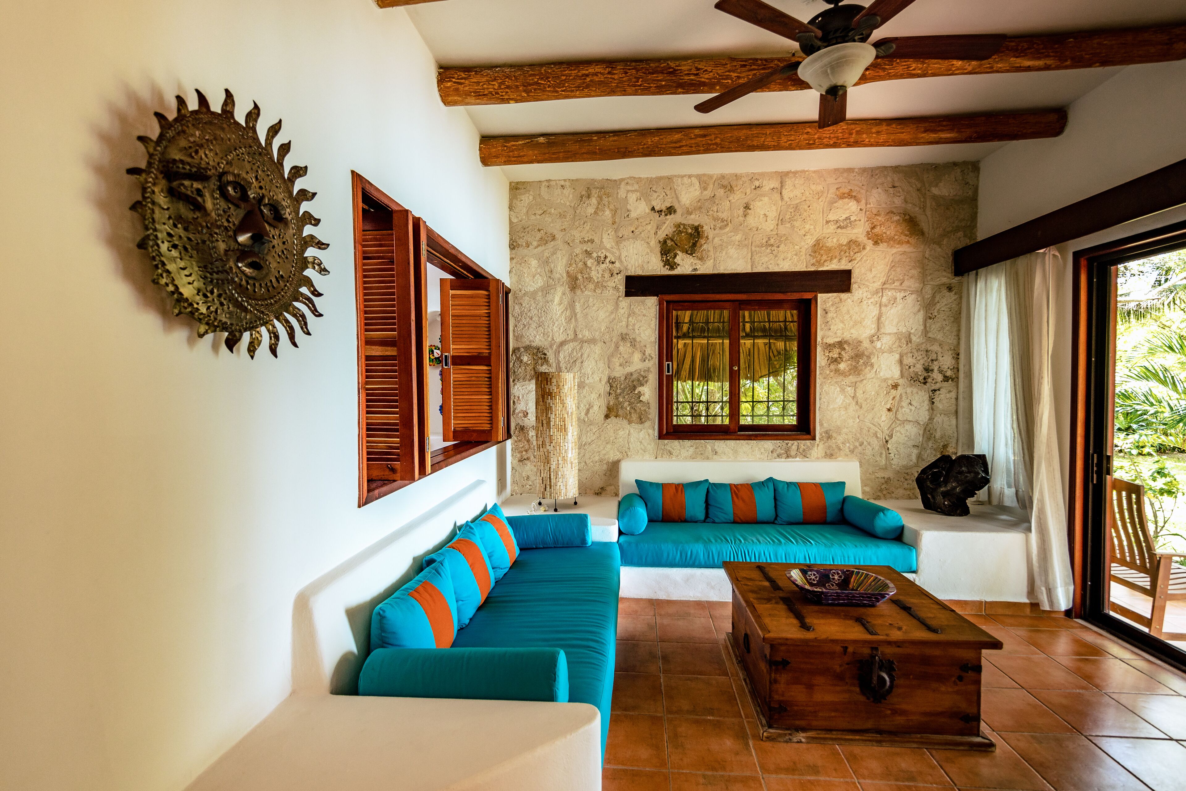 A living room with a stone wall, wooden ceiling beams, and a large window.