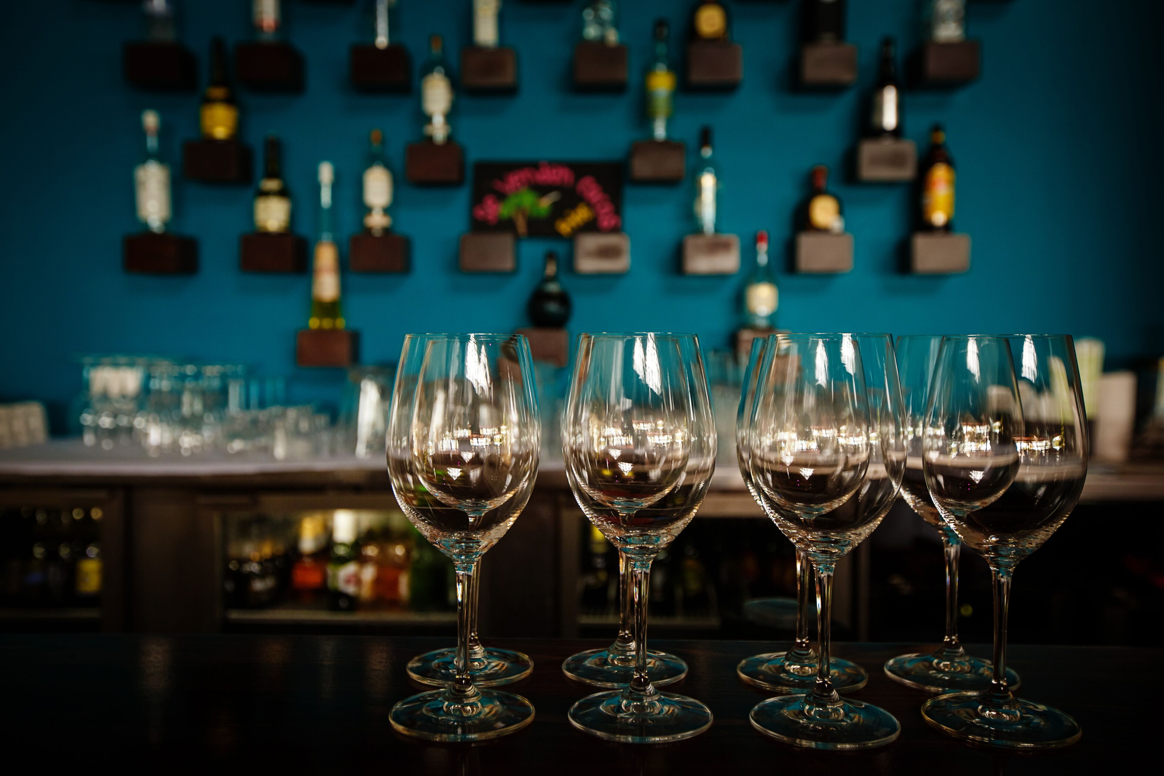 A bar area with multiple wine glasses and bottles on shelves.