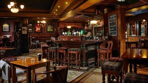 Un bar traditionnel avec des meubles en bois, un comptoir et un tableau affichant le menu.