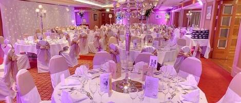 A banquet hall with round tables set for a formal event, each with numbered place cards.