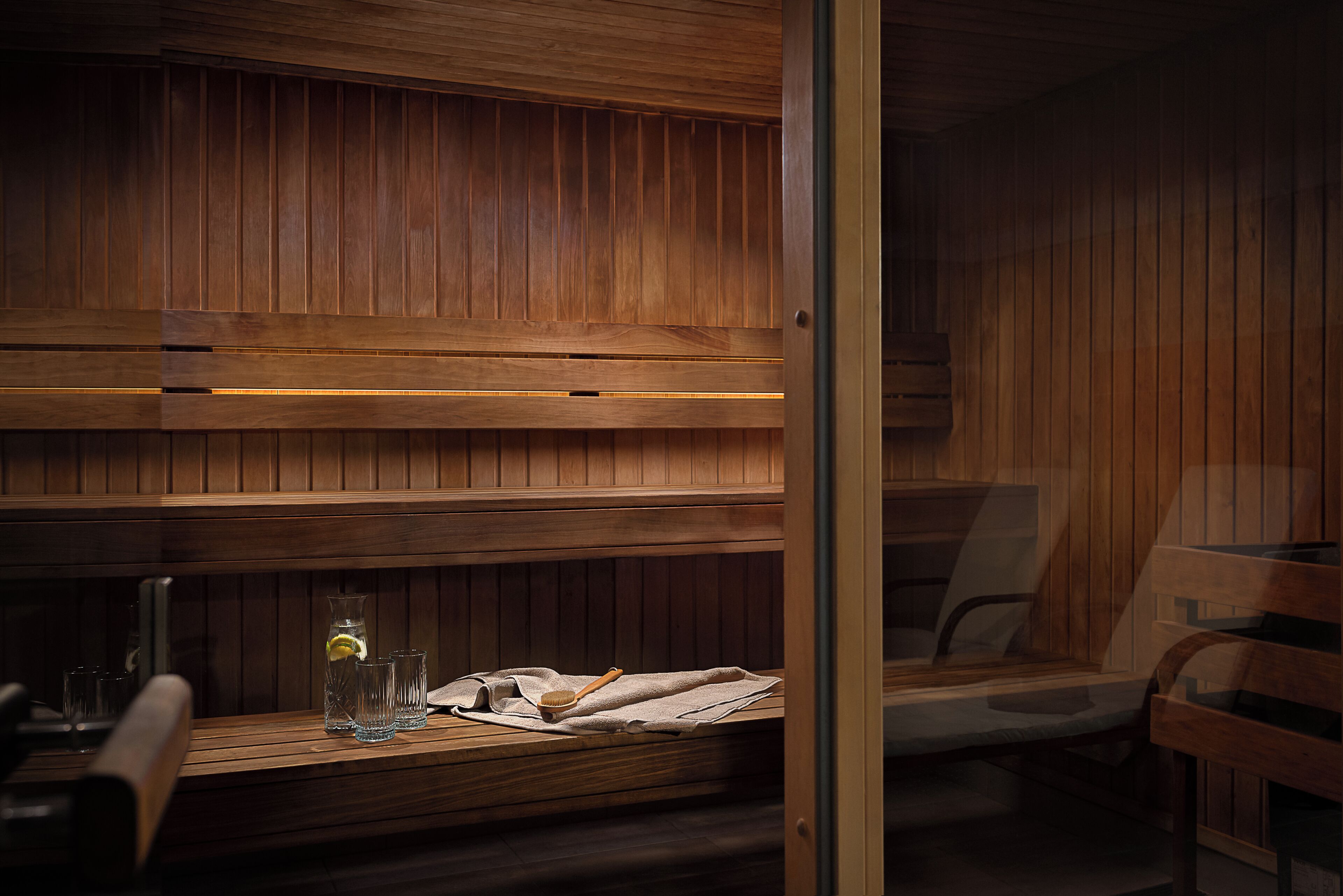 A sauna with wooden benches and a bench with a towel and a bottle.