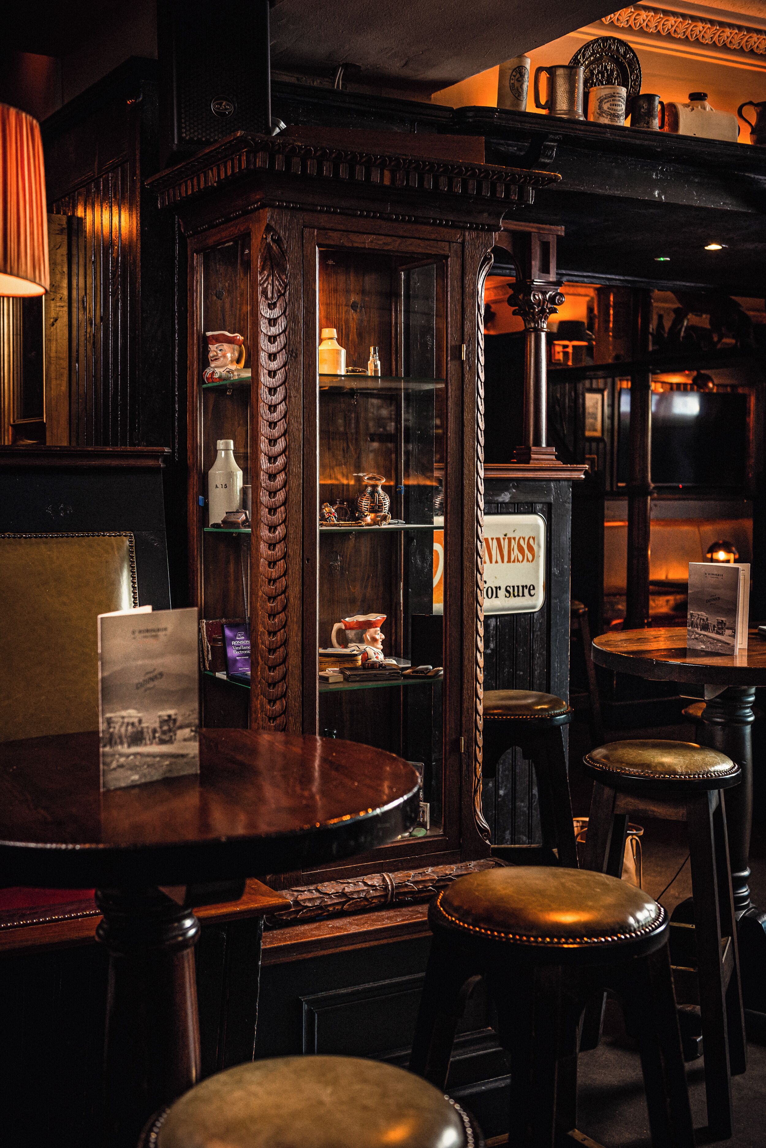 A bar area with wooden furniture, a sign reading 'NEVERNESS for sure,' and a vintage-style cabinet with glass doors.