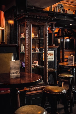 Una zona de bar con mobiliario de madera, un letrero que dice 'NEVERNESS for sure' y un aparador de estilo vintage con puertas de cristal.