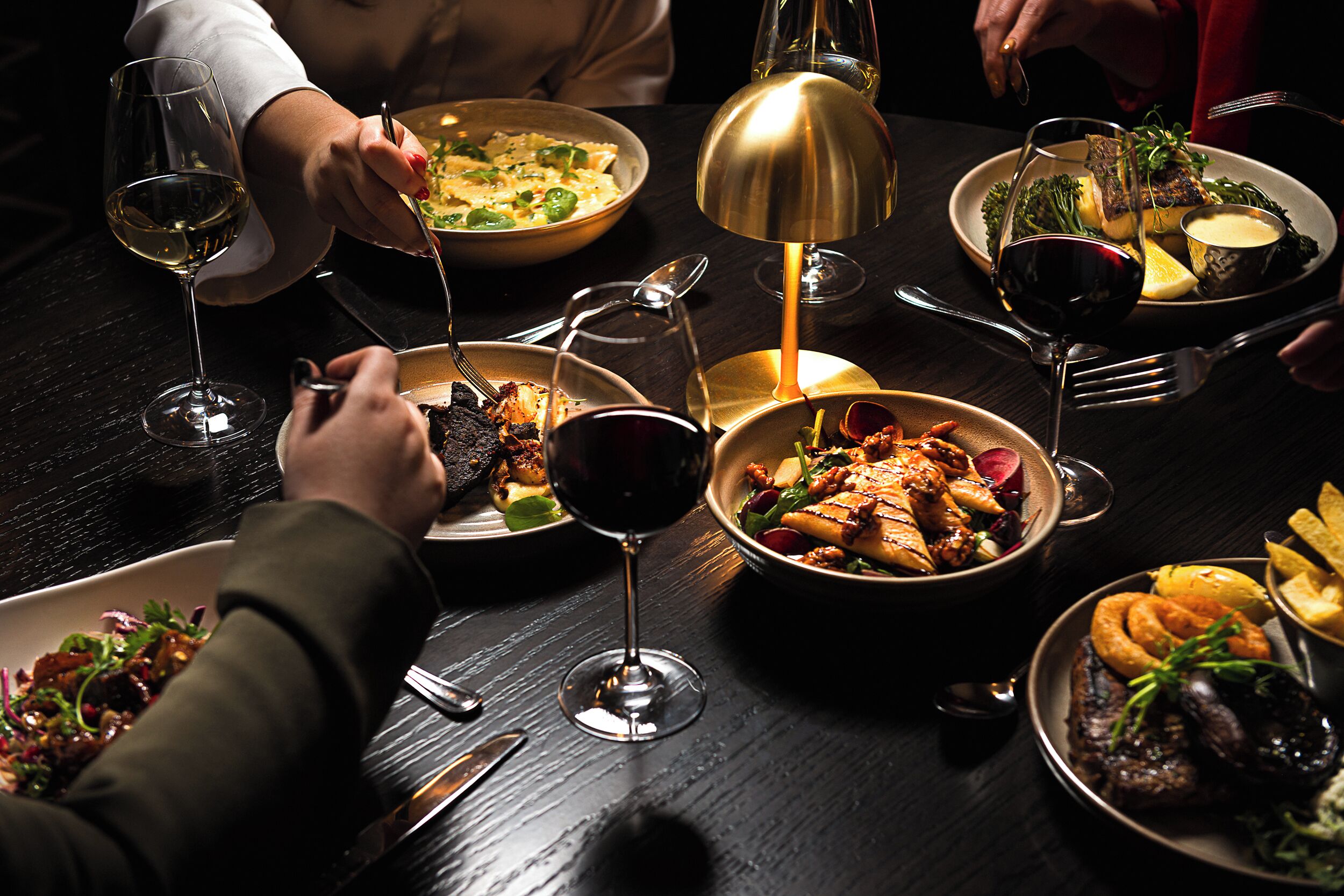 Une table à manger avec différents plats, des verres à vin et des couverts.