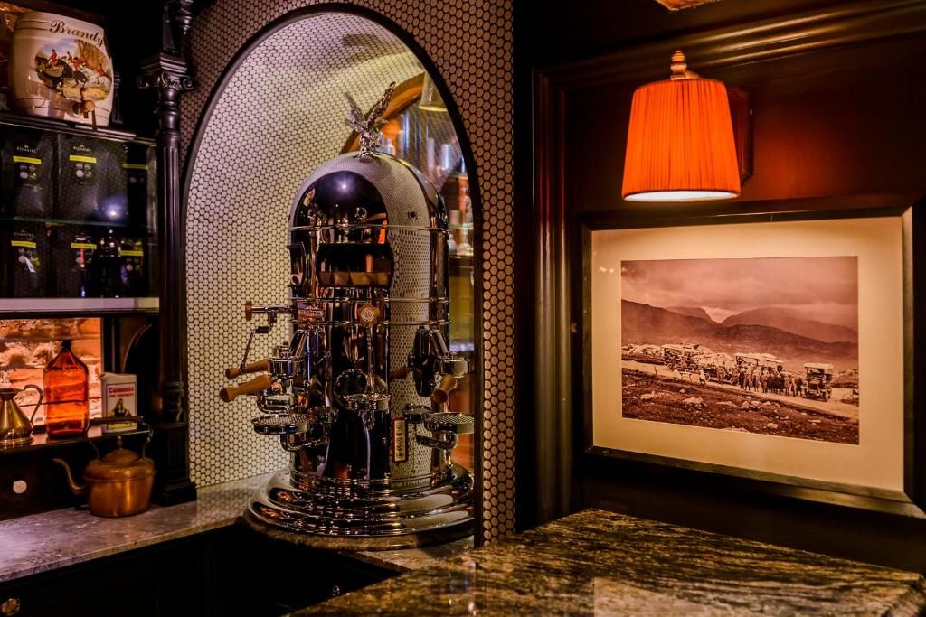 A vintage espresso machine, a framed historical photograph, and a bottle of Campari on a bar counter.