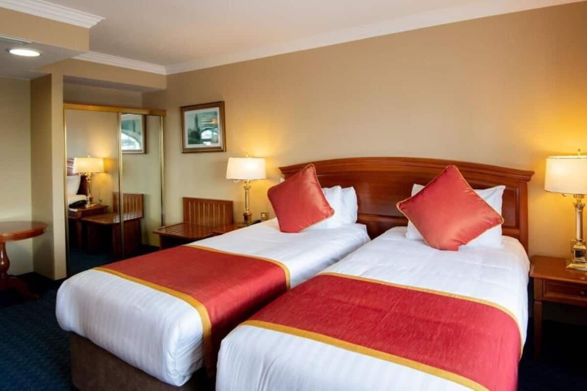Habitación de hotel con dos camas, un escritorio y una silla.