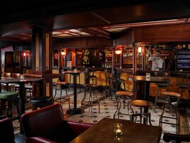 A bar area with wooden furniture, tables, and chairs.