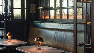 Una habitación con poca luz, un banco de madera, mesas y taburetes.