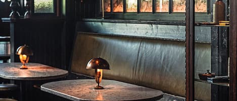 A dimly lit room with a wooden bench, tables, and stools.