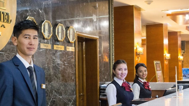 Un mostrador de recepción con una pared de mármol, relojes y un cartel que indica que el hotel está en Tokio.