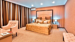 Una habitación de hotel con una cama grande, una silla, un escritorio y una mesita de noche.