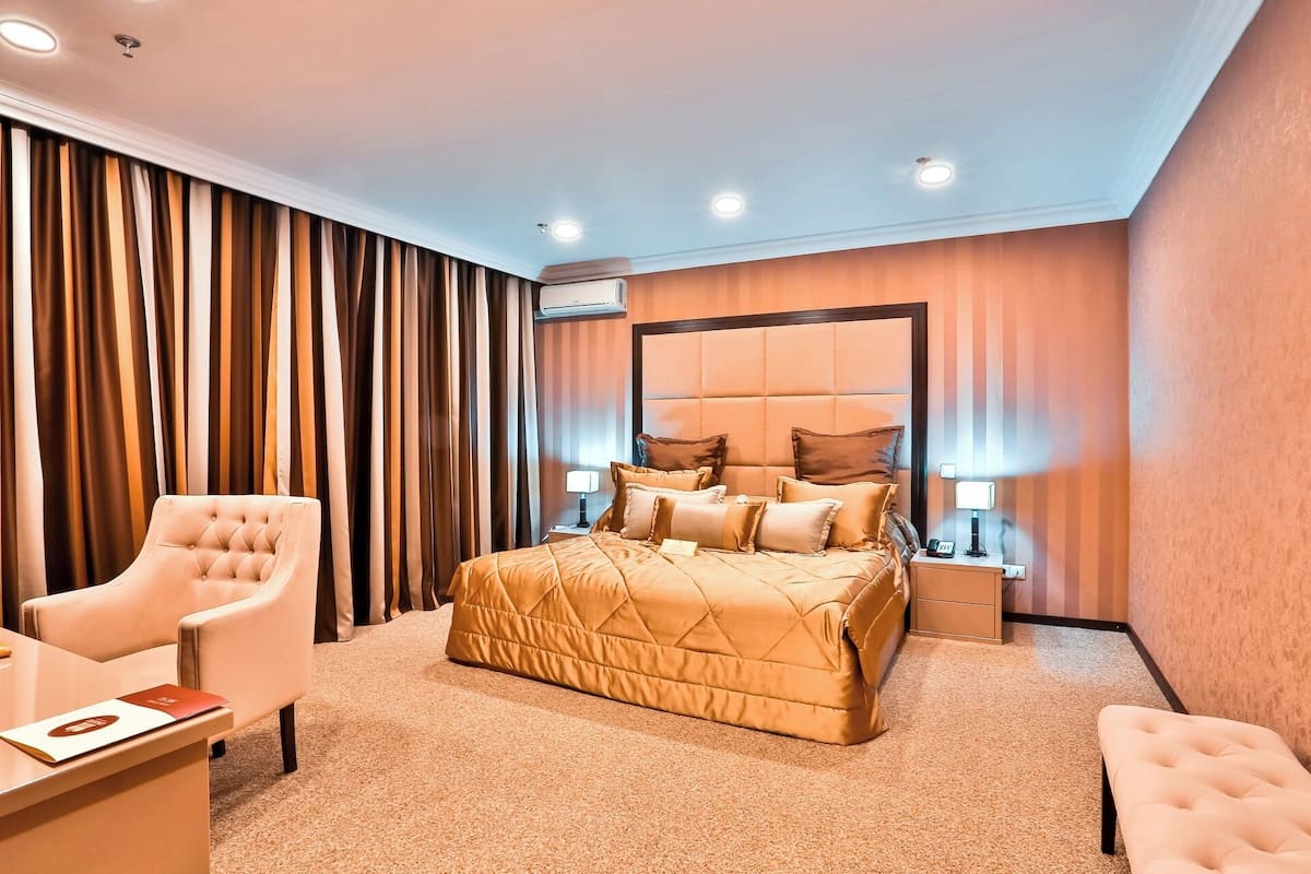 Una habitación de hotel con una cama grande, una silla, un escritorio y una mesita de noche.
