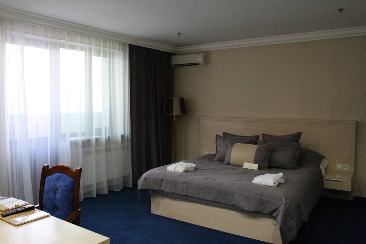 Habitación de hotel con una cama grande, un escritorio con una silla, una lámpara y un equipo de aire acondicionado.