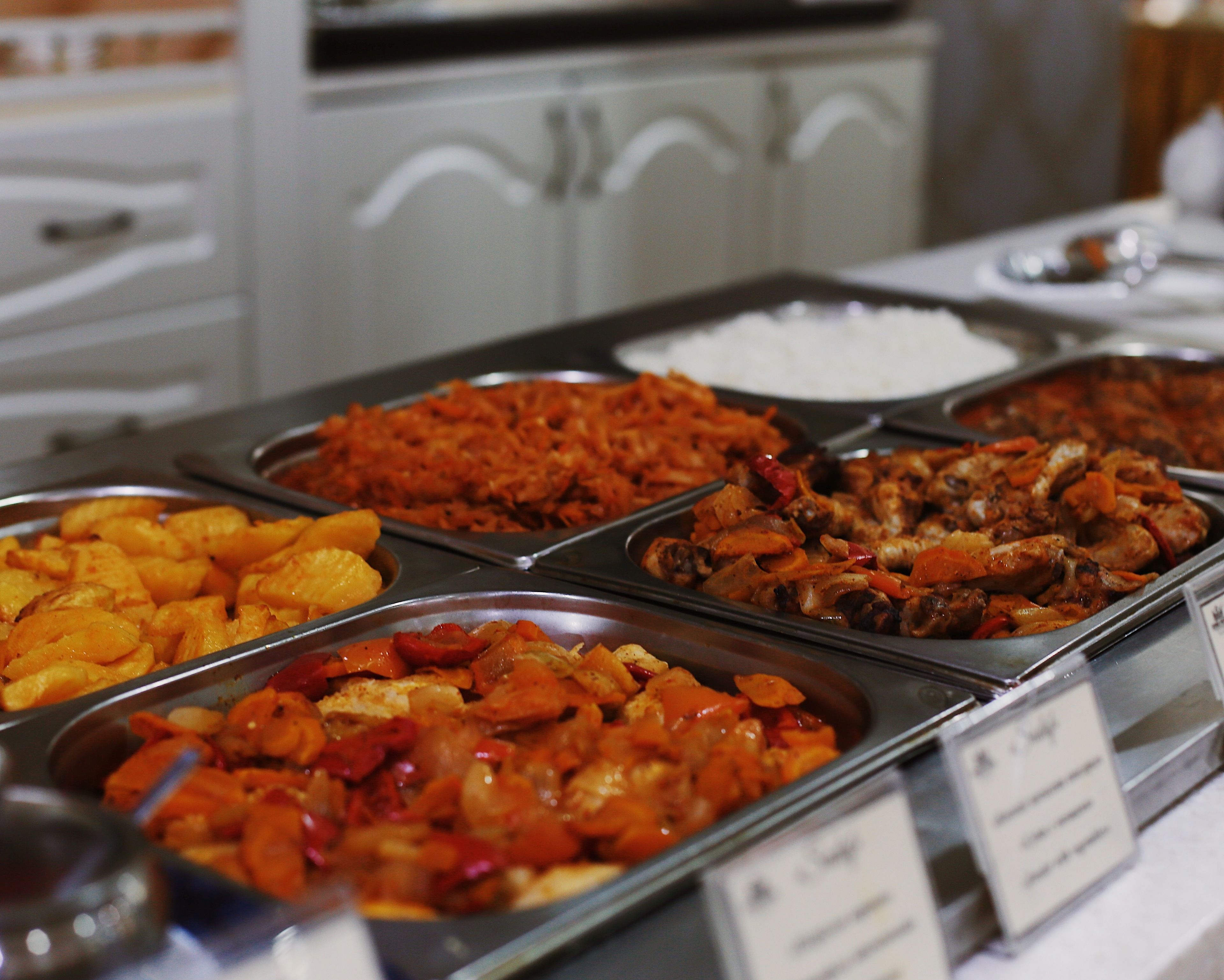 Buffet-pöydässä on tarjolla monenlaisia ruokia, kuten riisiä, kanaa ja kasviksia.