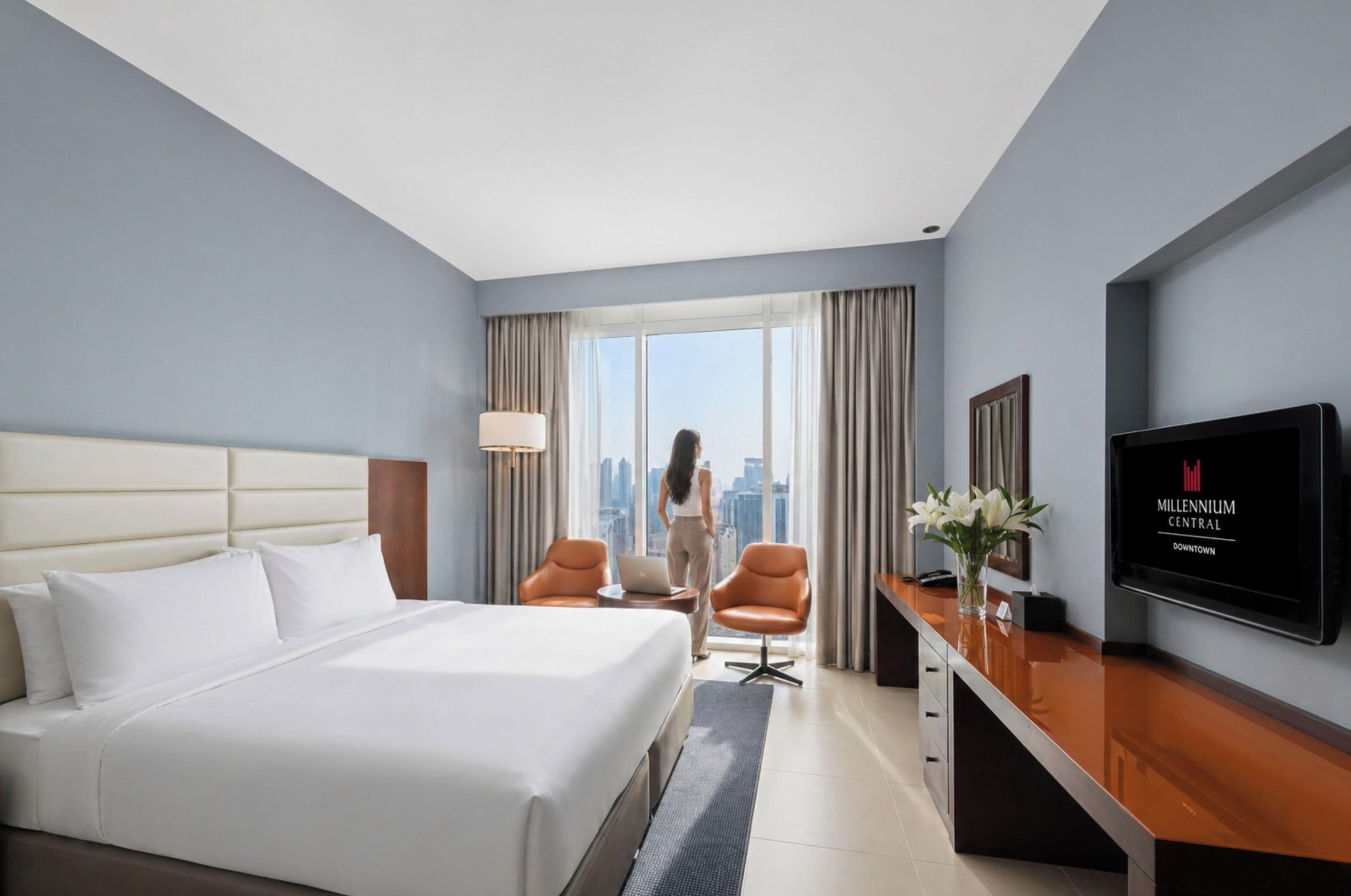 Ein Hotelzimmer mit Bett, Schreibtisch, Stuhl, Fernseher und Blick auf die Stadt.