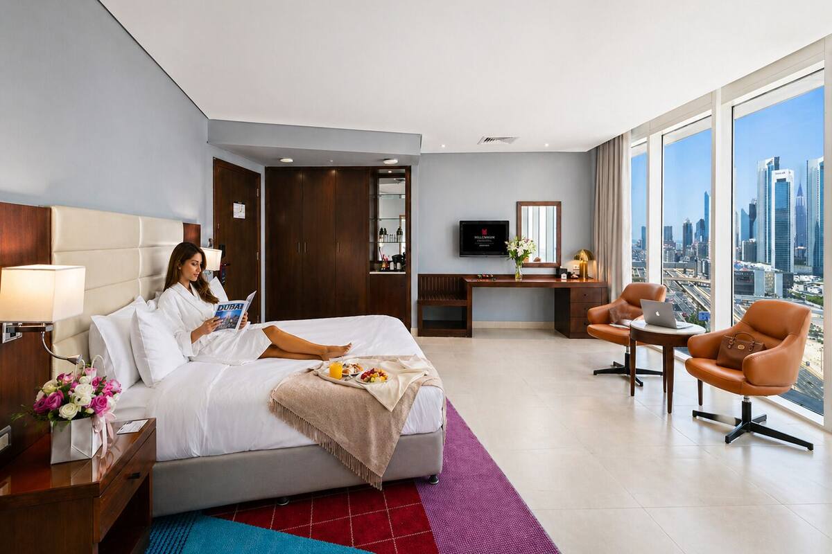 A hotel room with a bed, a desk, a TV, and a view of the city.