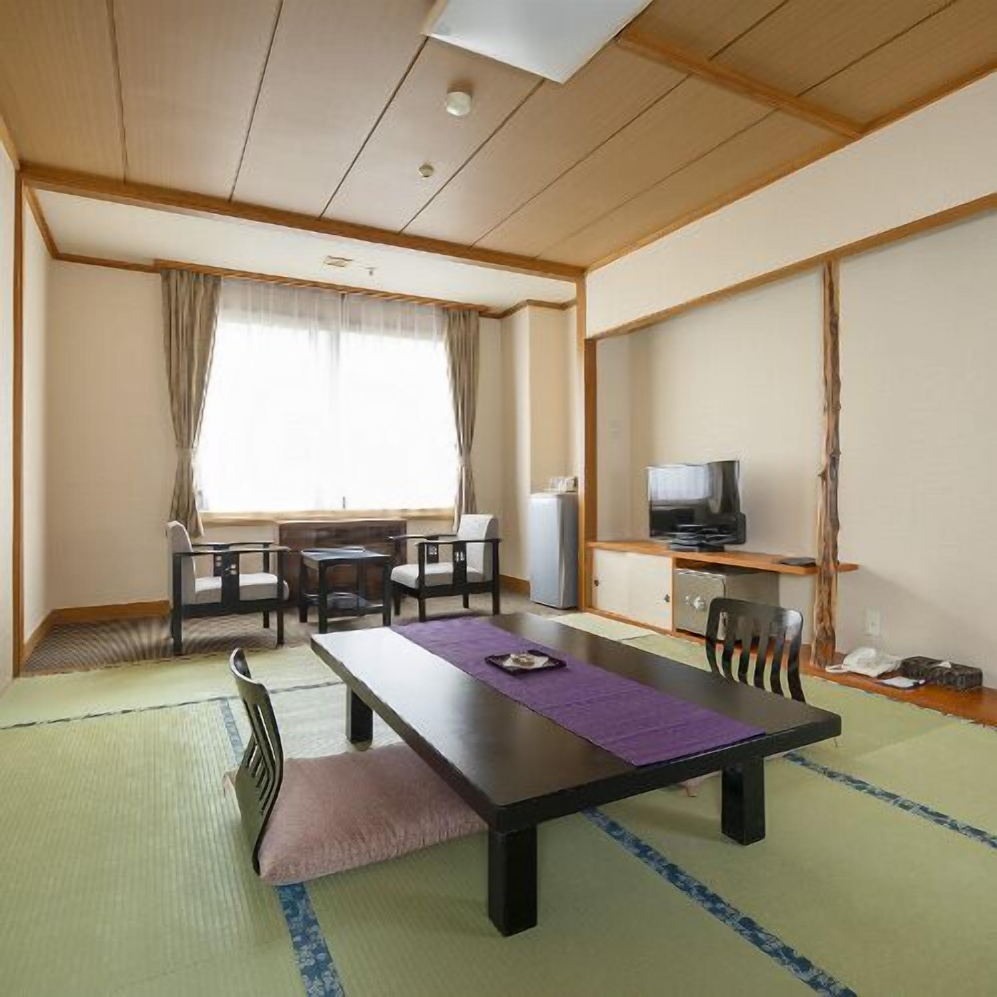 Une pièce avec un plafond en bois, une table à manger avec des chaises, un téléviseur et une petite kitchenette.