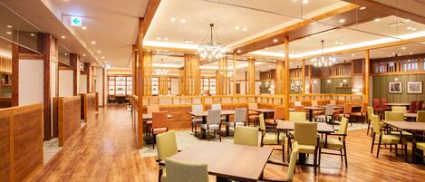 A spacious restaurant with wooden paneling, multiple seating areas, and a chandelier.
