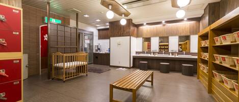 A hotel lobby with a wooden bench, a red storage unit, and a counter with baskets.