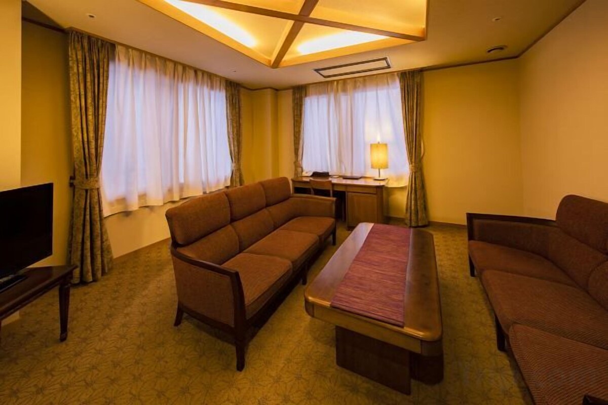 A hotel room with a sofa, a bed, a desk, and a television.