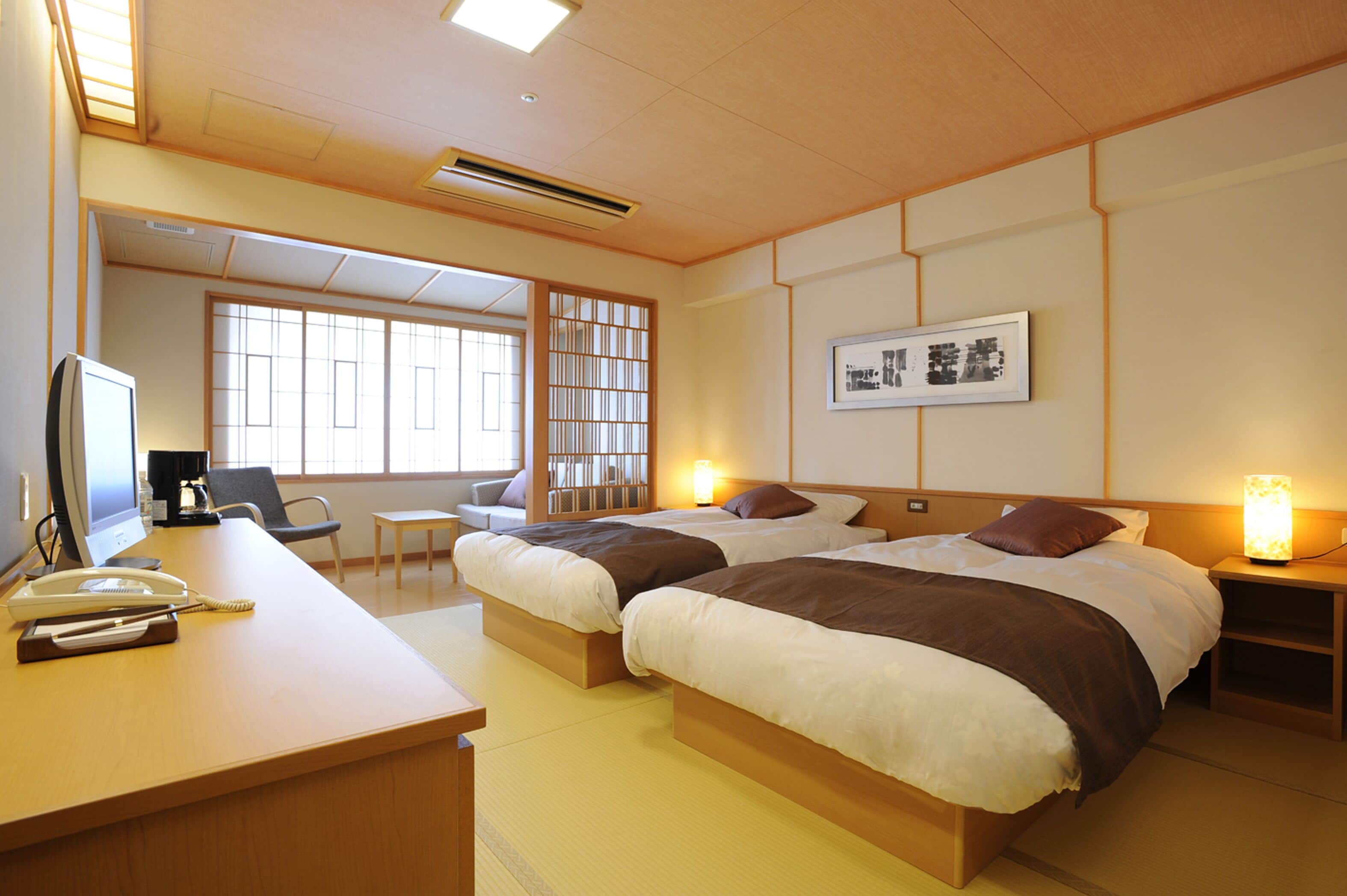 A hotel room with two beds, a desk with a telephone, a chair, and a small table.