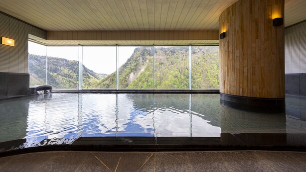 Una piscina interior tranquila con vistas despejadas a un paisaje montañoso a través de amplios ventanales.
