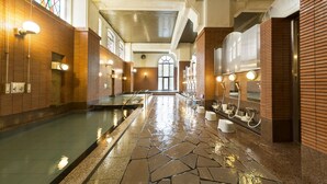 Un área de piscina larga y estrecha con suelo de baldosas, bancos y una pared de cristal.