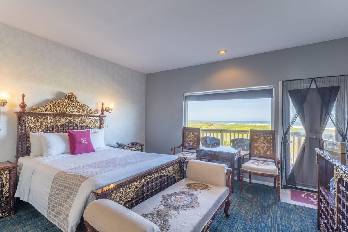 A hotel room with a large bed, a balcony with a view, and a desk with a chair.