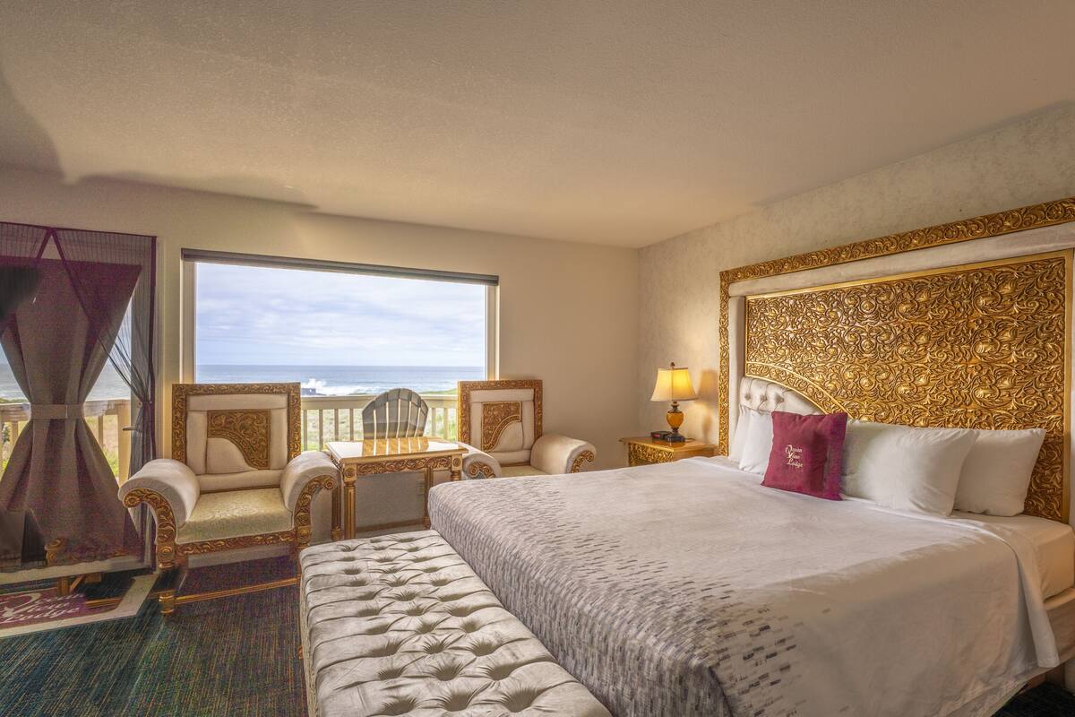 A hotel room with a large bed, a chair, a desk, and a view of the ocean.
