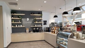 A modern cafe interior with a counter, shelves with items, and a display case with pastries. - University of British Columbia - UBC Okanagan Campus (Kelowna)
