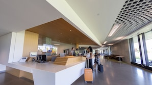 A modern reception area with a wooden reception desk, computers, and a seating area with a bench. - University of British Columbia - UBC Okanagan Campus (Kelowna)