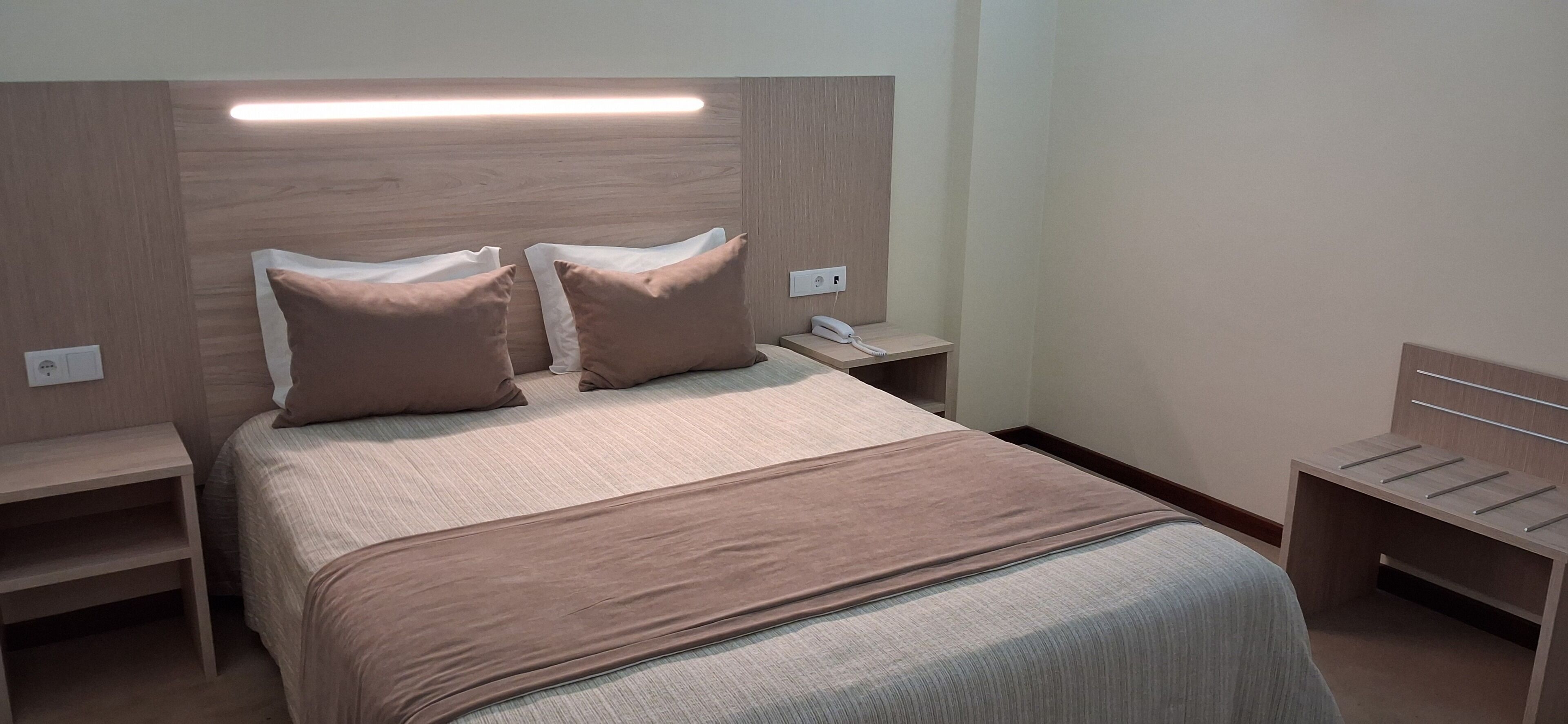 Ein Hotelzimmer mit Bett, Nachttischen, einer Nachttischlampe und einem Telefon.