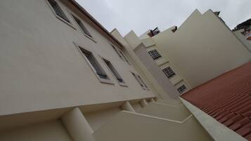 Un edificio de varios pisos con un estilo arquitectónico moderno, que presenta una serie de ventanas y un tejado de tejas rojas.