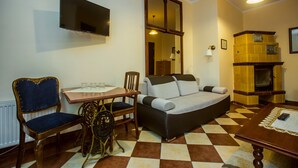 A living room with a sofa, chairs, a table, a flat-screen TV, a fireplace, and a checkered floor. - Pod Kasztanami (Swinoujscie)