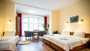 A hotel room with two beds, a dining table, chairs, a potted plant, and a view of the outdoors. - Pod Kasztanami (Swinoujscie)