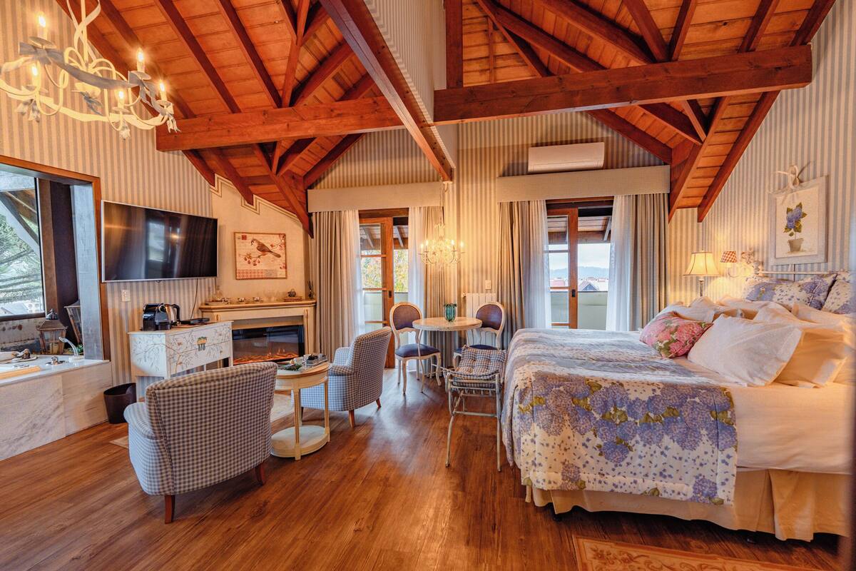 A room with a bed, a TV, a desk, and a chandelier.