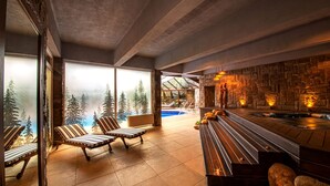 Un moderno espacio de spa con pared de piedra, una bañera de hidromasaje y vistas a la piscina.