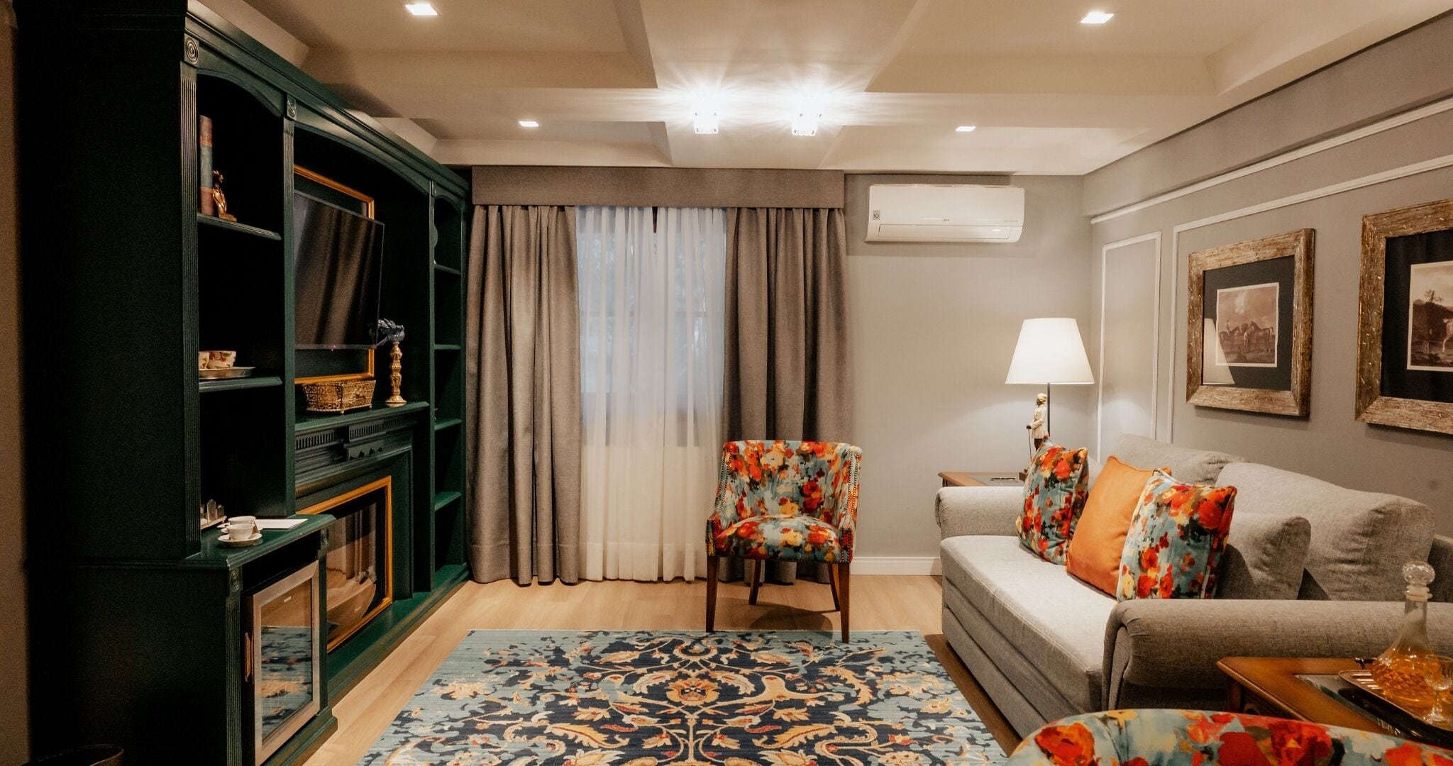 Una sala de estar con un sofá, una silla, una estantería y una alfombra estampada.