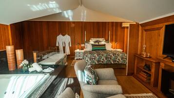 Quarto com cama, mesa de cabeceira e televisão.