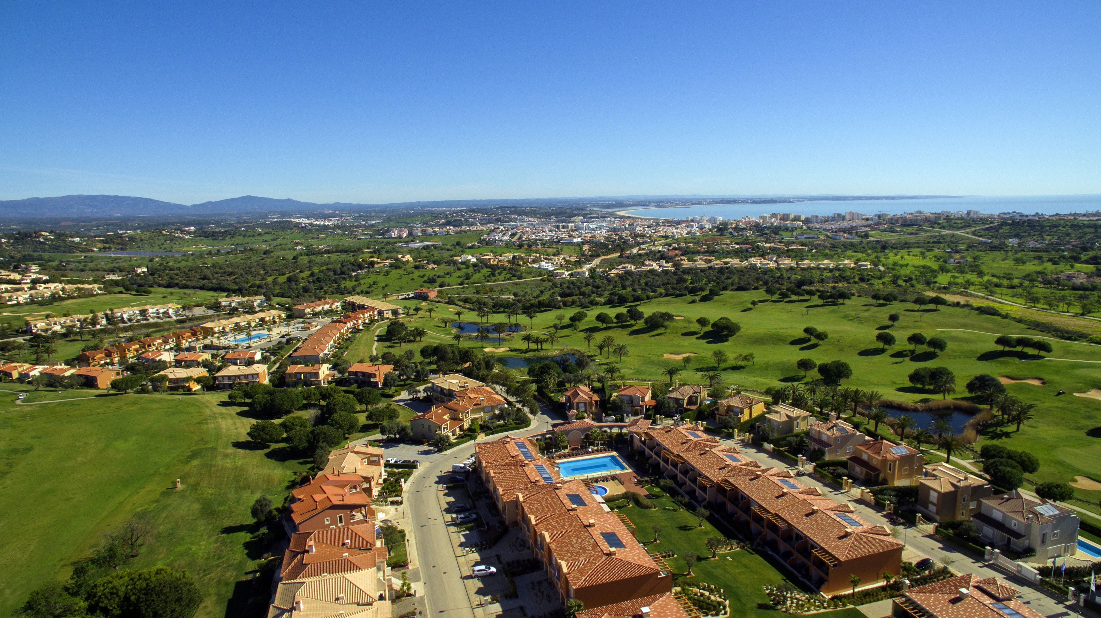 An aerial view of a resort with multiple buildings, green lawns, and a golf course.