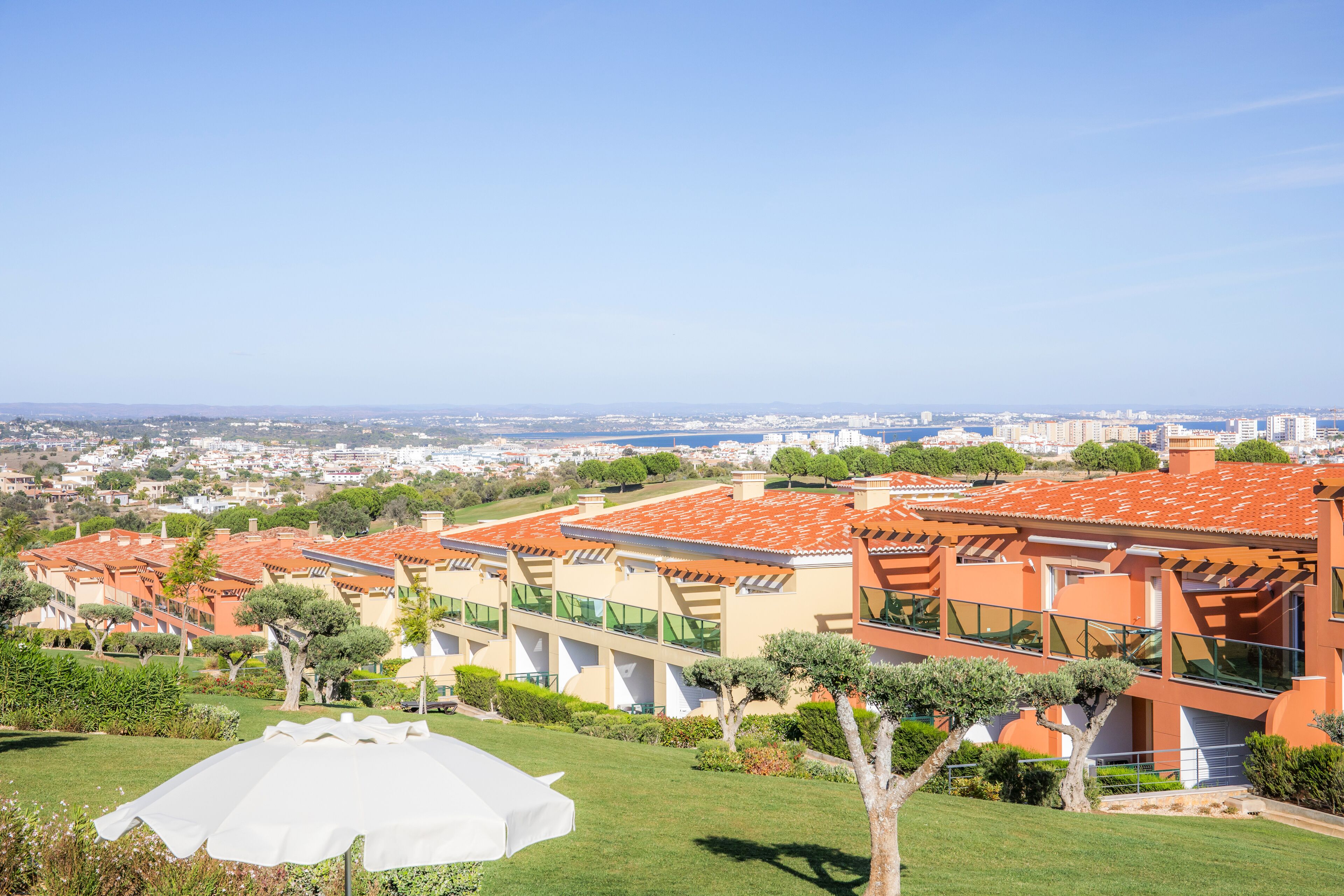 Zona residencial con edificios modernos, cielo despejado y una vista distante de la ciudad.