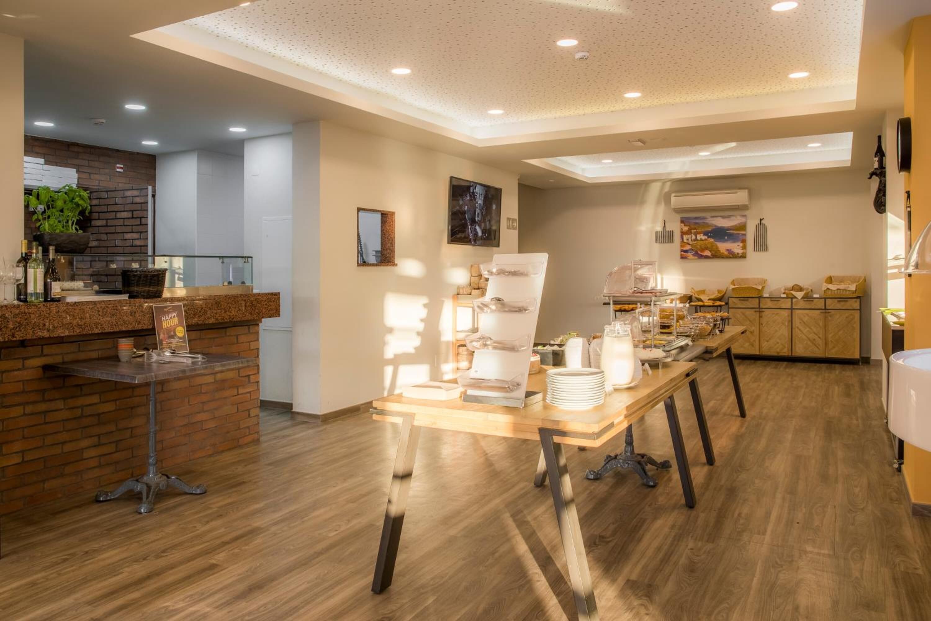 A modern hotel lobby with a reception desk, a buffet table, and a seating area.