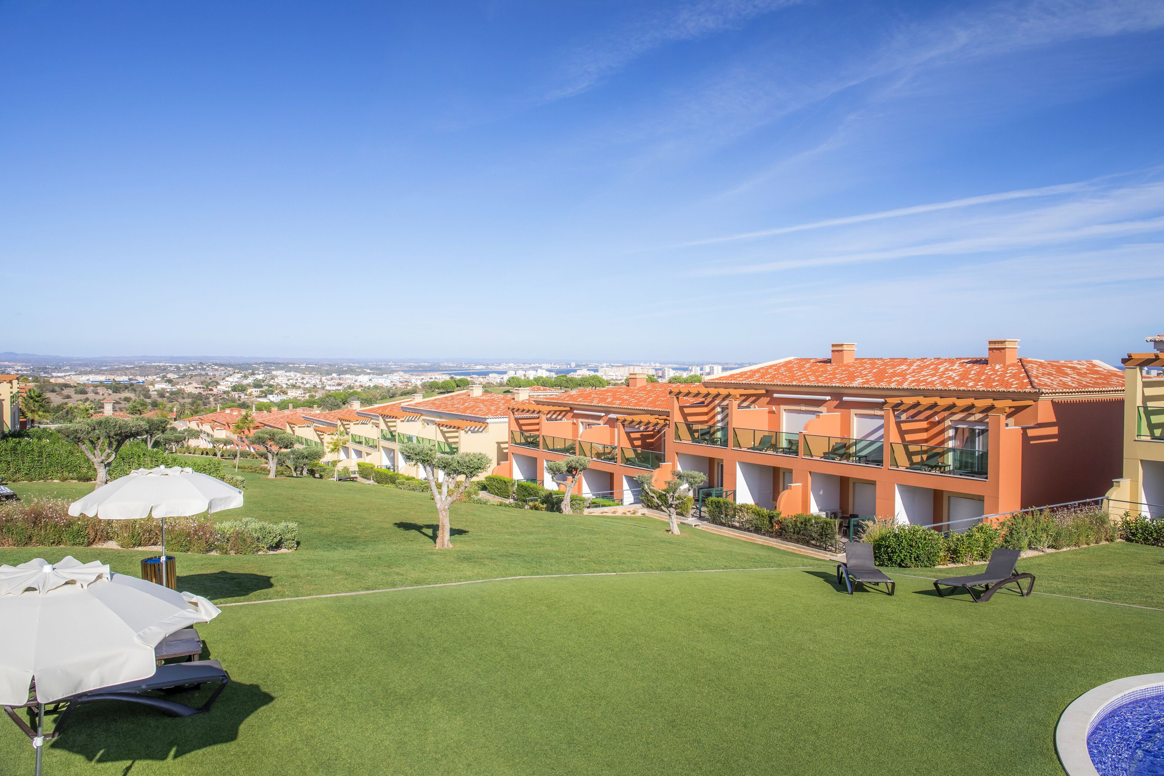 A resort with multiple buildings, a swimming pool, and outdoor seating areas.