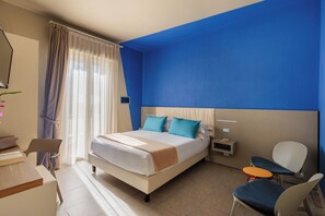 A modern hotel room with a bed, a desk, a chair, and a small table. - Hotel Nina (Bibbona)
